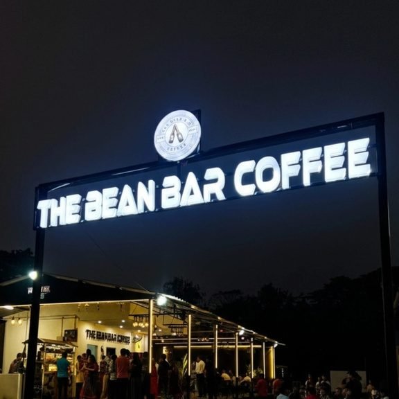 The Bean Bar Coffee stall lit up at night with the logo sign