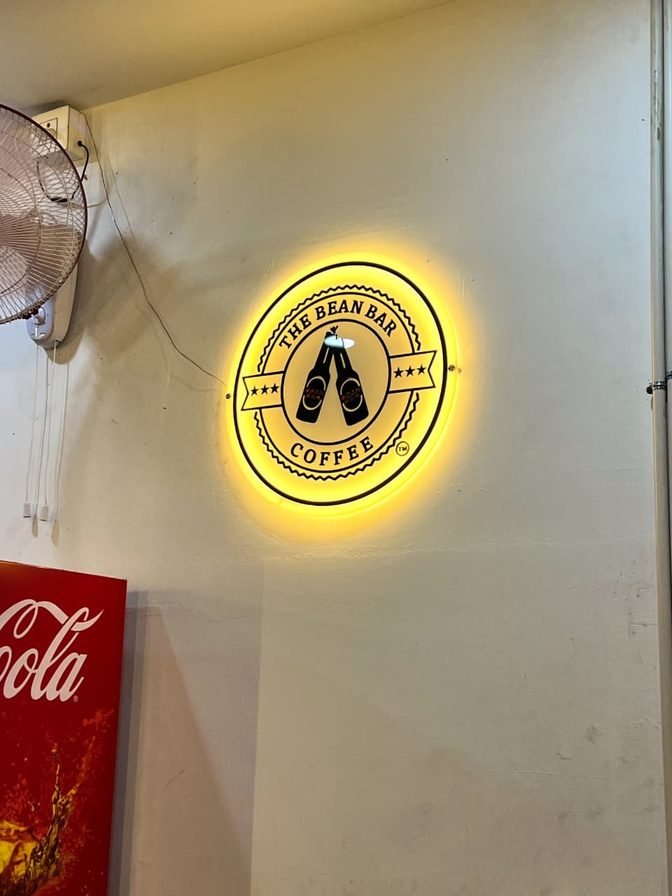 The Bean Bar Coffee logo sign backlit in gold on a wall